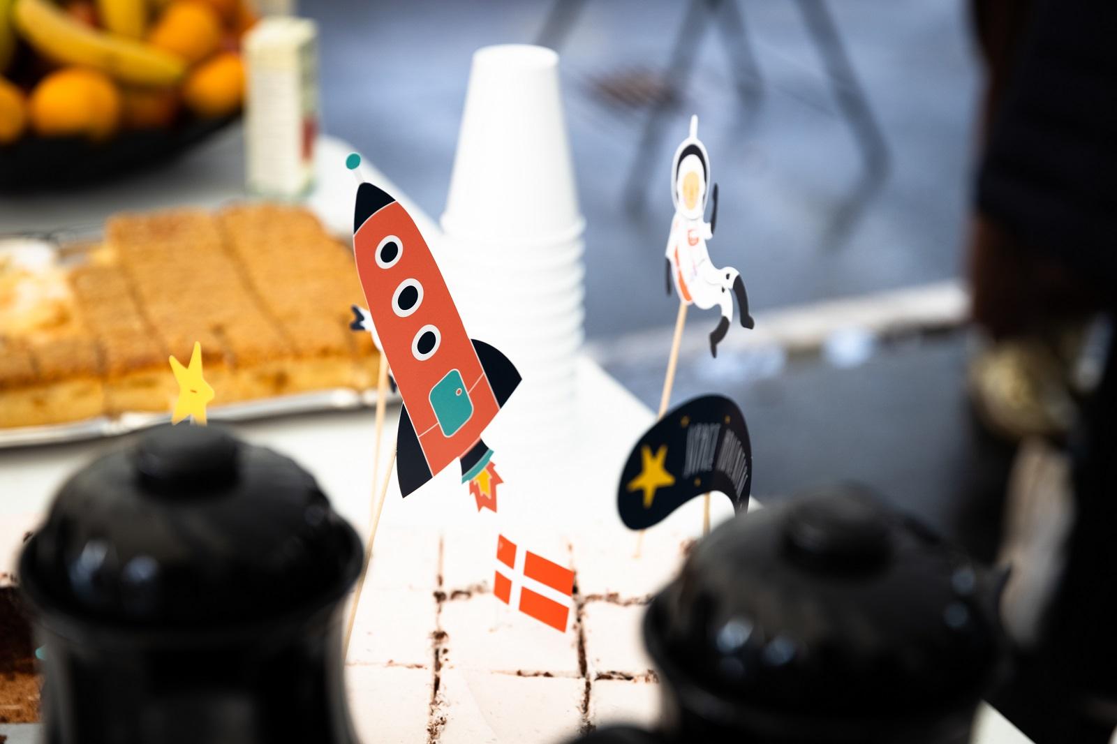 Papfigurer som raket og astronaut på et bord med kaffe og kage